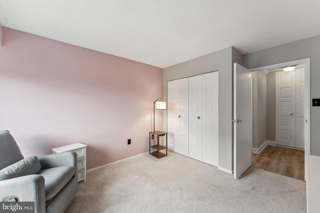 living area featuring carpet flooring, baseboards, and a textured ceiling