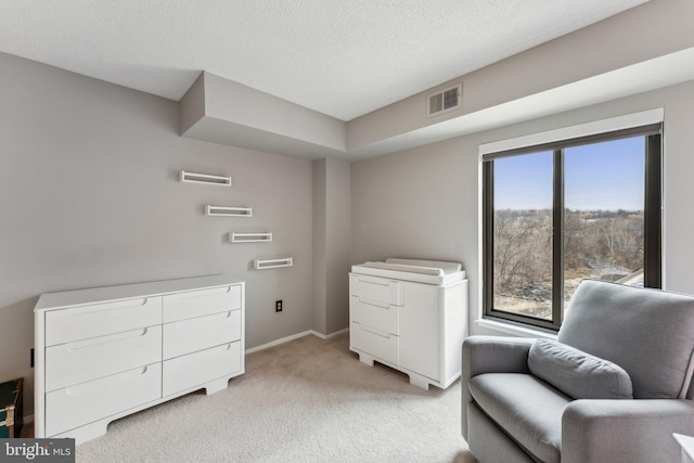 sitting room with visible vents, baseboards, light colored carpet, and a textured ceiling