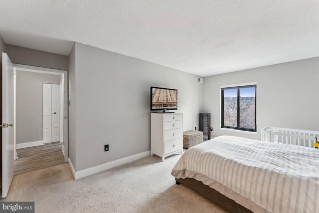 carpeted bedroom featuring baseboards and a textured ceiling