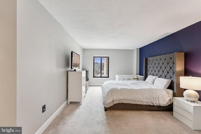 bedroom with a textured ceiling, baseboards, and light carpet