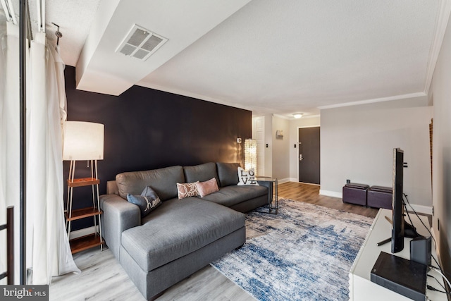 living area featuring crown molding, wood finished floors, visible vents, and baseboards