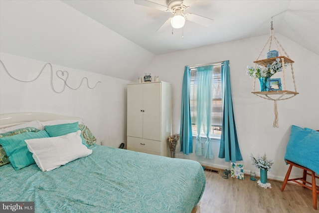 bedroom with wood finished floors, visible vents, baseboards, ceiling fan, and vaulted ceiling