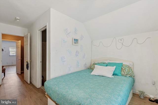 bedroom featuring vaulted ceiling, wood finished floors, and baseboards