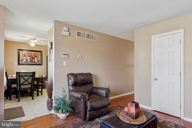 sitting room featuring light wood-type flooring, visible vents, baseboards, and ceiling fan