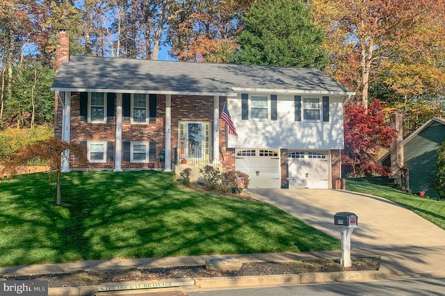 raised ranch featuring brick siding, concrete driveway, a front yard, a chimney, and a garage