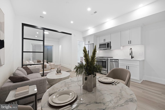 dining room featuring light wood-type flooring, visible vents, baseboards, and recessed lighting