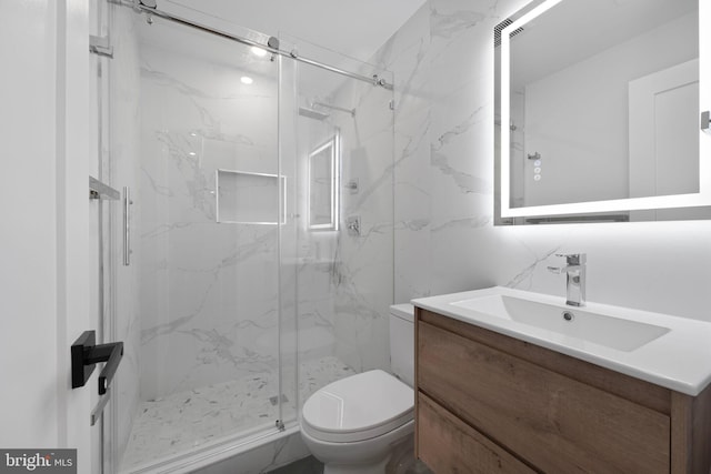 bathroom with a marble finish shower, vanity, and toilet