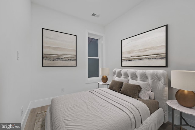 bedroom featuring baseboards, visible vents, and wood finished floors