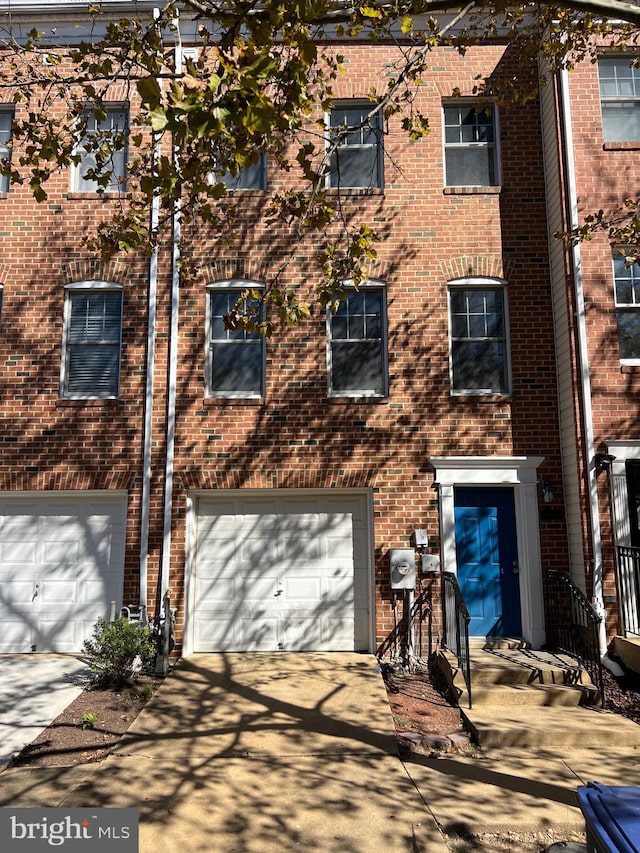 view of property with a garage, brick siding, and driveway