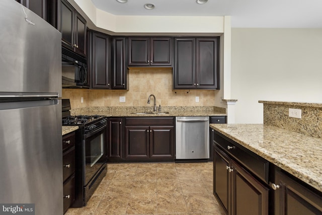 kitchen featuring backsplash, light stone counters, recessed lighting, black appliances, and a sink