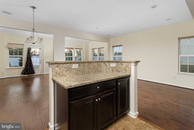 kitchen with light stone counters, baseboards, dark wood-style floors, and hanging light fixtures