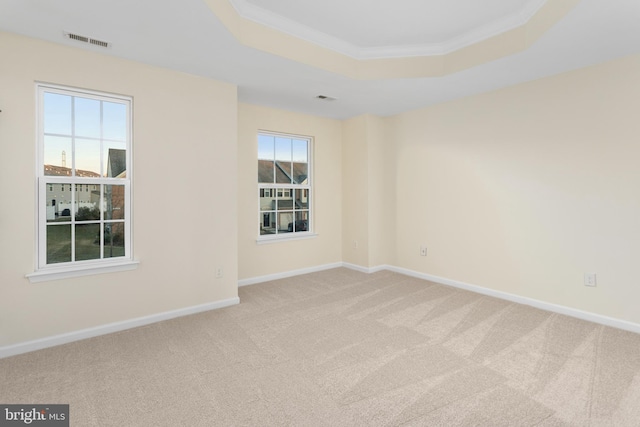 empty room with visible vents, crown molding, baseboards, light colored carpet, and a tray ceiling