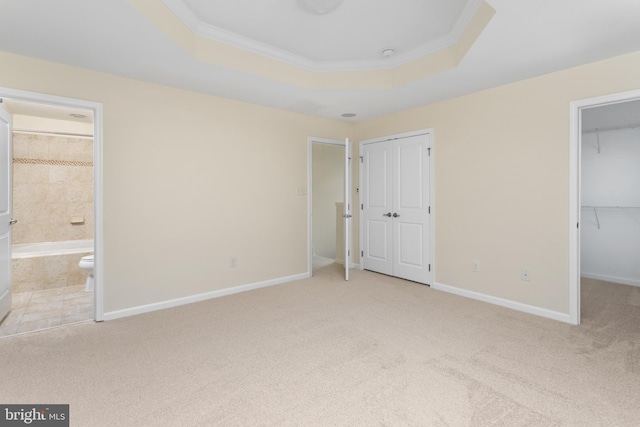 unfurnished bedroom with carpet floors, baseboards, a tray ceiling, and ornamental molding