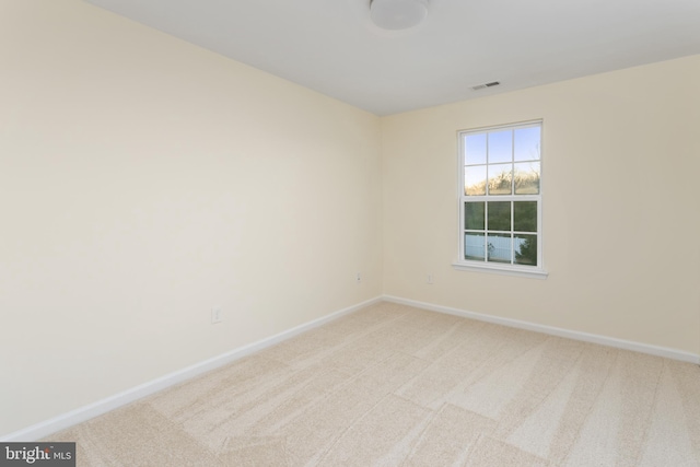 spare room with baseboards and light carpet