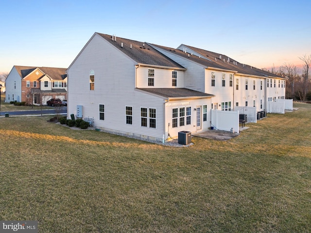 back of house with central air condition unit and a yard