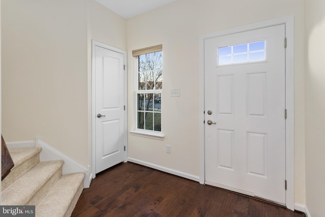 foyer featuring dark wood finished floors, stairs, and baseboards