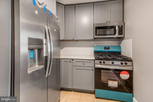 kitchen with tasteful backsplash, gray cabinets, stainless steel appliances, and light countertops