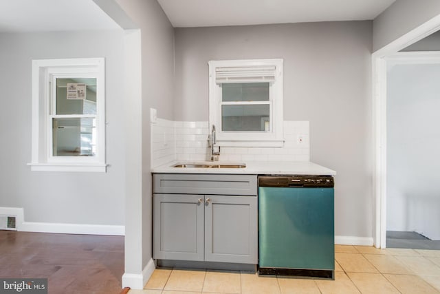 kitchen featuring a sink, tasteful backsplash, dishwasher, and gray cabinetry