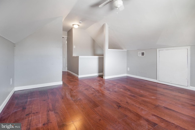 additional living space featuring baseboards, visible vents, a ceiling fan, hardwood / wood-style floors, and vaulted ceiling