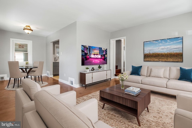 living area featuring baseboards, visible vents, and wood finished floors