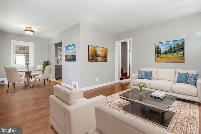 living room with wood finished floors, visible vents, and baseboards