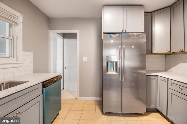 kitchen featuring light stone counters, light tile patterned floors, gray cabinetry, stainless steel fridge, and dishwashing machine