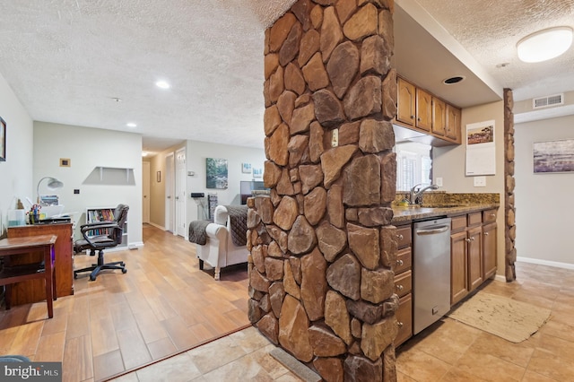 kitchen featuring visible vents, a sink, stainless steel dishwasher, a textured ceiling, and open floor plan