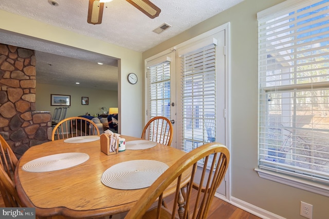 dining area with wood finished floors, french doors, visible vents, and a textured ceiling