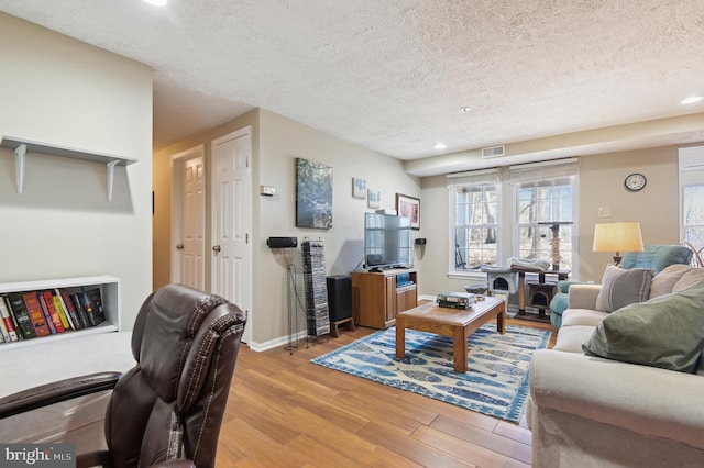 living room featuring visible vents, baseboards, light wood-type flooring, recessed lighting, and a textured ceiling