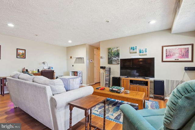 living area with visible vents, recessed lighting, a textured ceiling, and wood finished floors