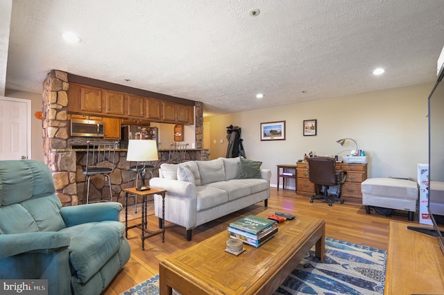 living room featuring recessed lighting, light wood-type flooring, and a textured ceiling