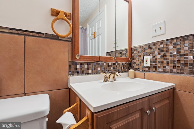 bathroom with vanity, tile walls, toilet, and a textured ceiling