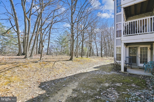 view of yard featuring french doors, a balcony, and a patio area