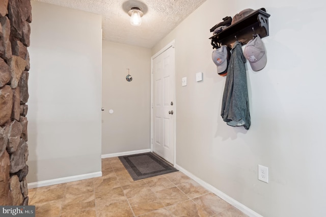 interior space with a textured ceiling and baseboards