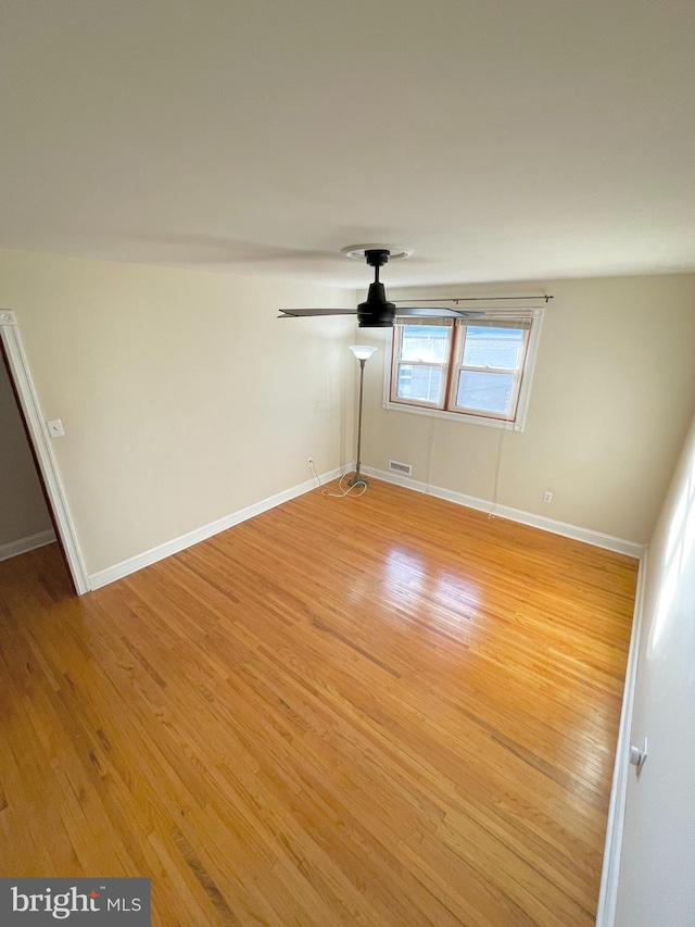 empty room with light wood finished floors, ceiling fan, and baseboards