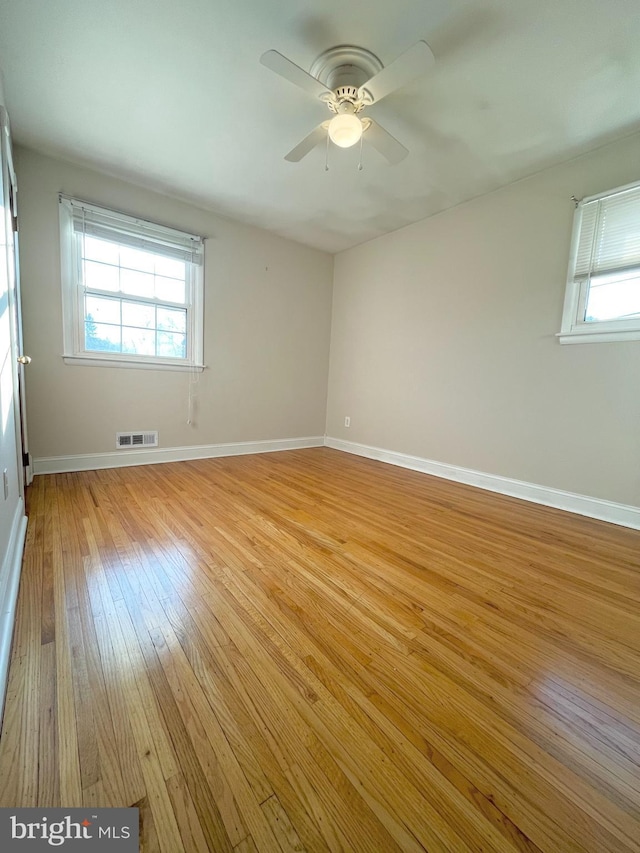 unfurnished room with baseboards, a healthy amount of sunlight, visible vents, and light wood-style floors