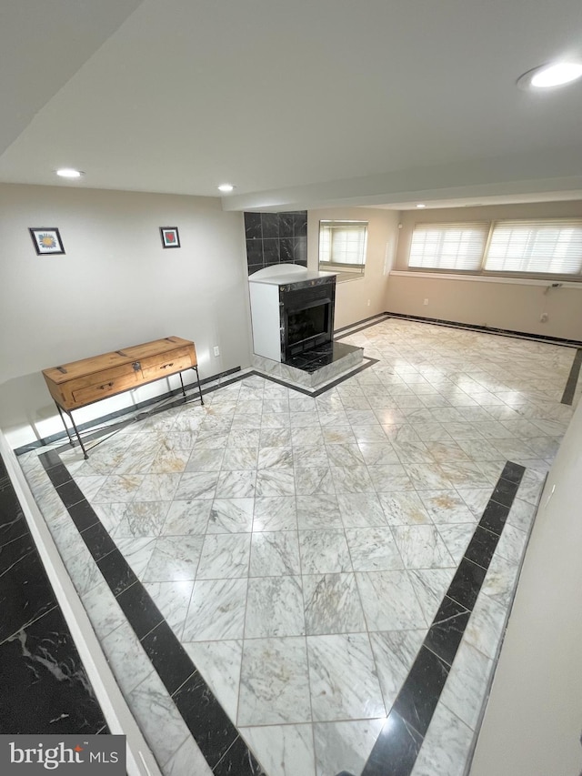 unfurnished living room with recessed lighting, marble finish floor, and baseboards