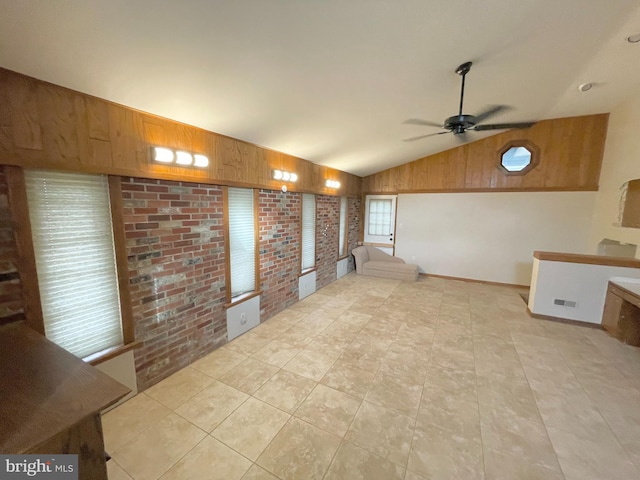 interior space featuring light tile patterned floors, vaulted ceiling, wooden walls, brick wall, and ceiling fan