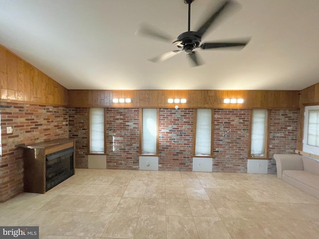 unfurnished living room featuring wood walls, brick wall, a fireplace, and vaulted ceiling