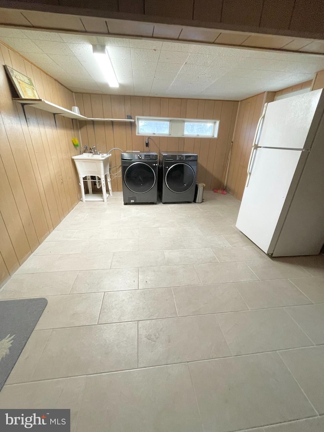 laundry room with laundry area, wooden walls, a sink, and independent washer and dryer