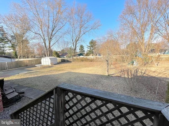 view of yard featuring an outbuilding, a patio, a storage shed, and a fenced backyard