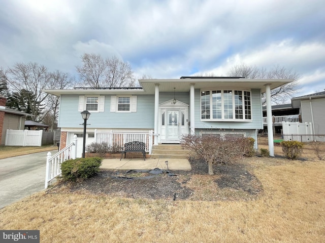 bi-level home featuring concrete driveway and fence