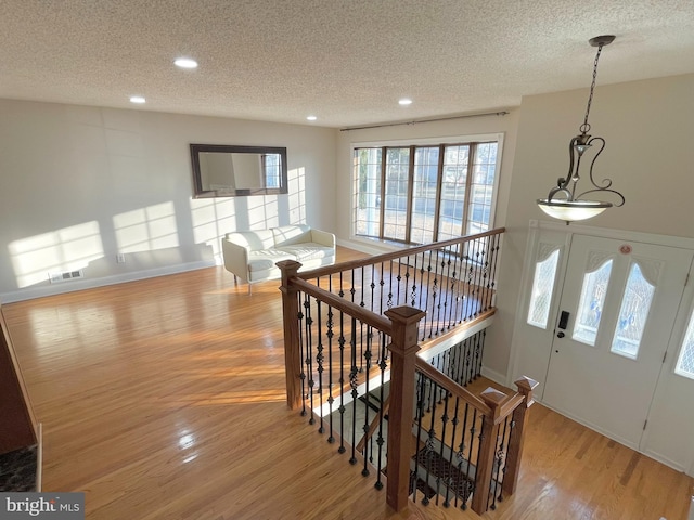 foyer entrance featuring light wood-style flooring, visible vents, and a textured ceiling