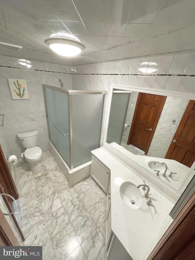 bathroom with tile walls, marble finish floor, visible vents, and a shower stall