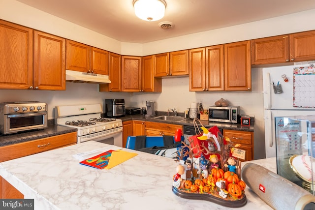 kitchen with white appliances, visible vents, brown cabinetry, under cabinet range hood, and a sink