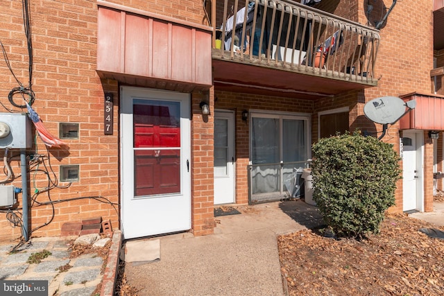 property entrance with a balcony and brick siding