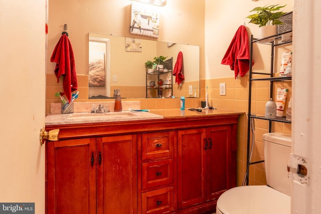 half bath featuring a wainscoted wall, tile walls, toilet, and vanity