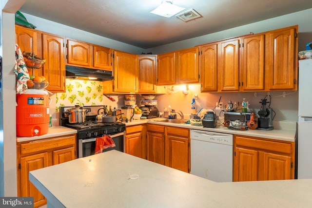 kitchen featuring under cabinet range hood, white appliances, a sink, light countertops, and brown cabinetry