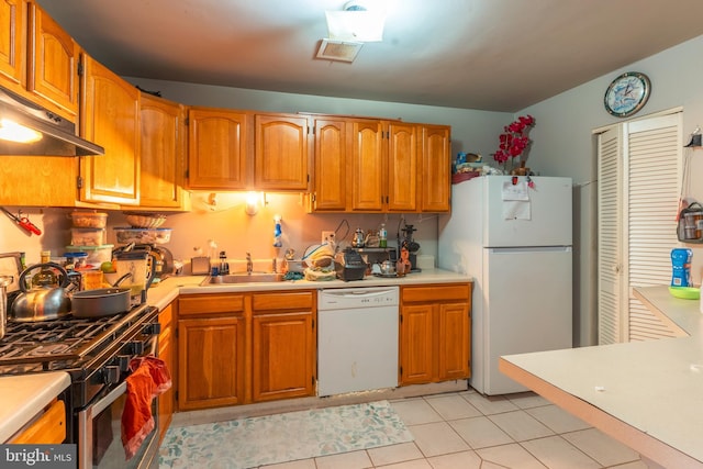 kitchen featuring white appliances, light countertops, a sink, and brown cabinetry