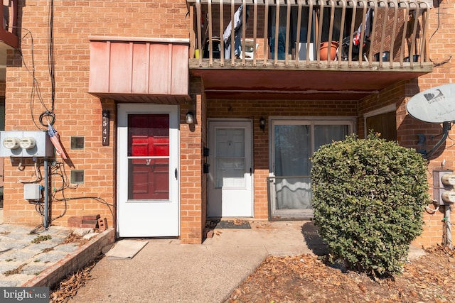 doorway to property featuring a balcony and brick siding